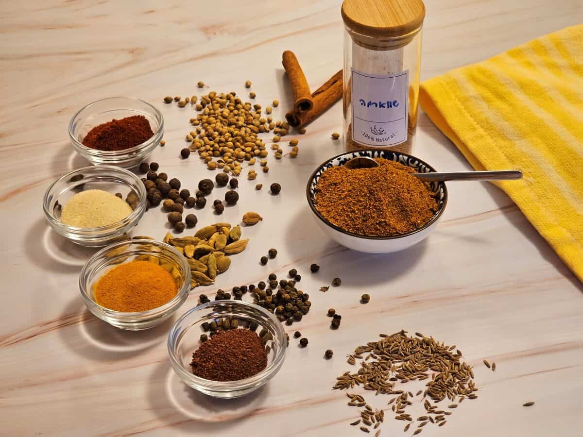 Homemade shawarma spice blend in a bowl, with a spoonful of spices scattered around.