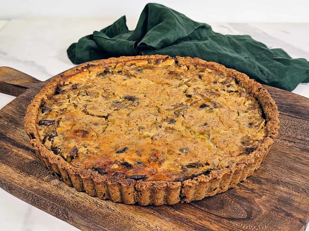 Vegan gluten-free mushroom and chestnut quiche placed on a rustic wooden surface, featuring a rich filling and crispy crust.