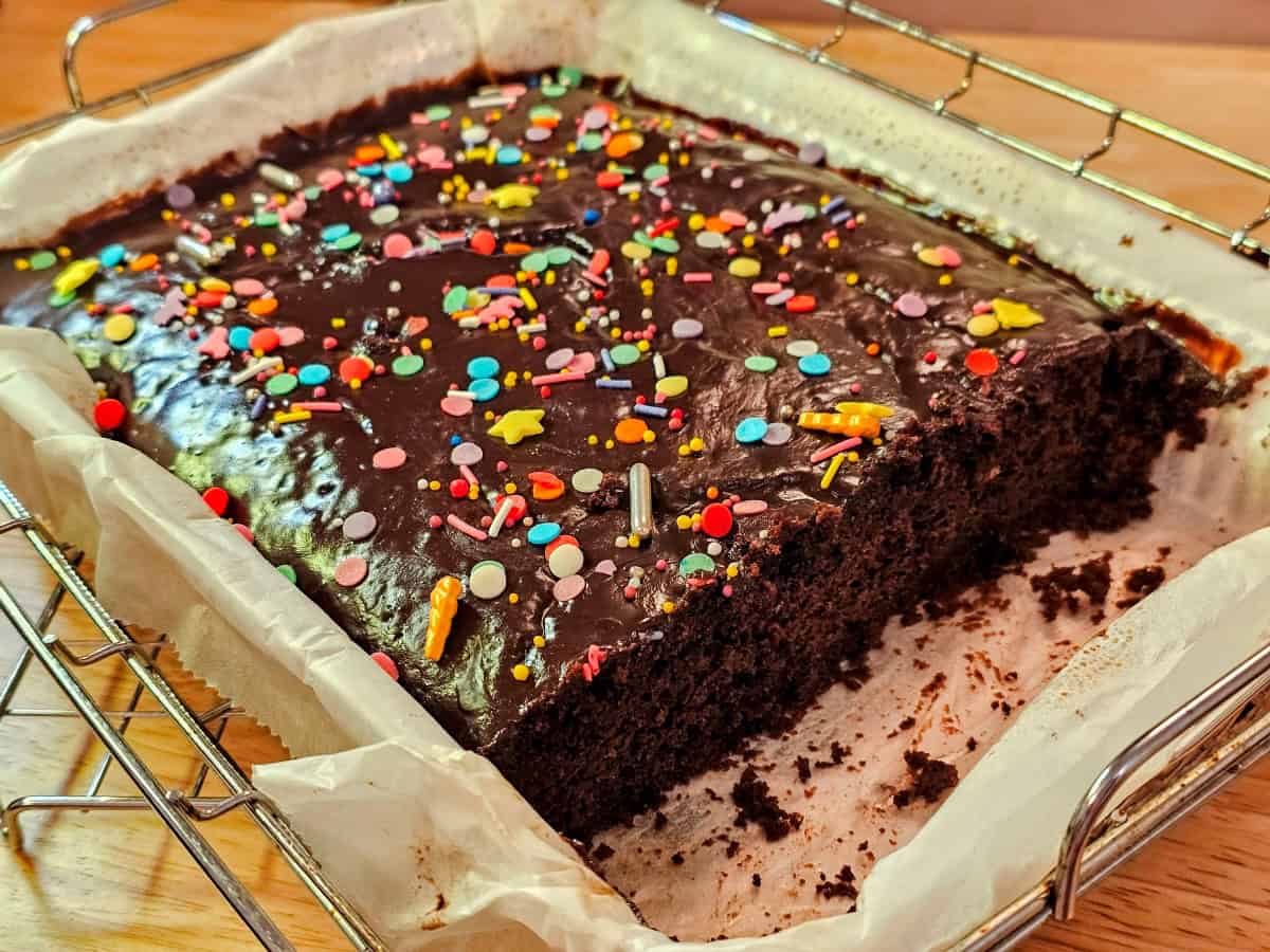 Vegan chocolate cake in a baking dish with one slice cut out, side view