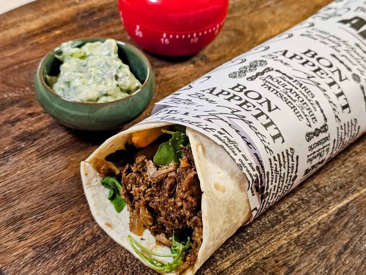 Vegan gyros pita wrap with tzatziki, arugula, tomatoes, and fries