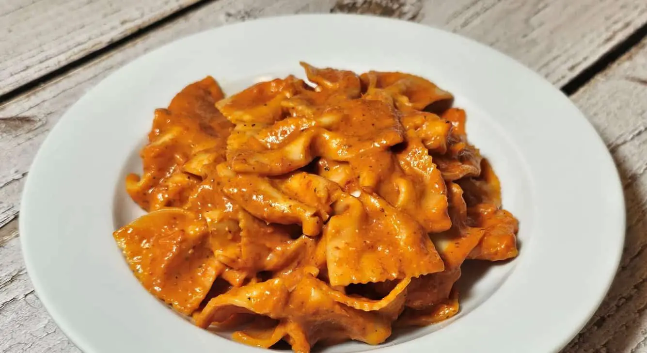 Pasta in creamy roasted pepper sauce with vegan goat cheese.