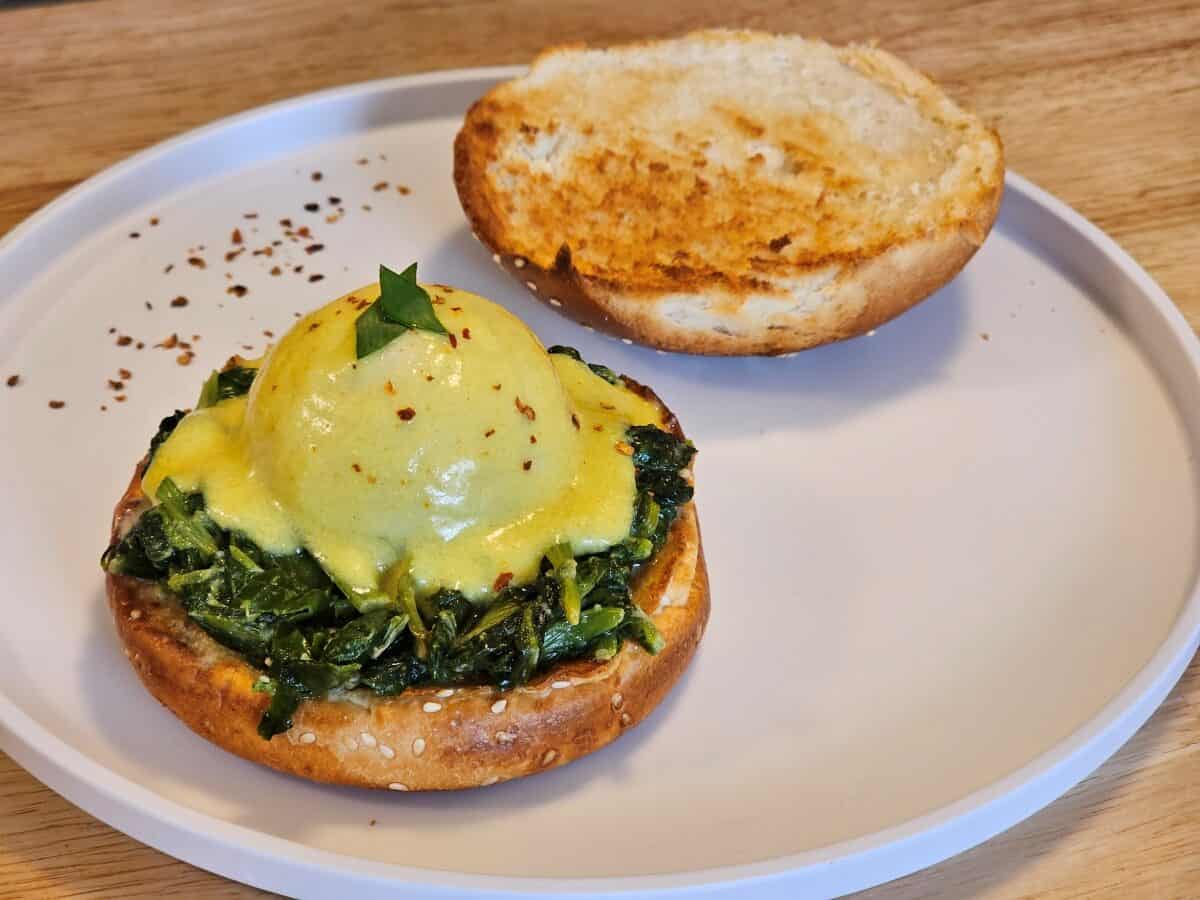 Vegan eggs benedict with rich hollandaise sauce over sautéed spinach and a toasted bun – a beautifully tempting dish